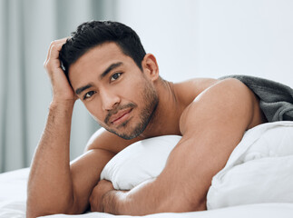 Morning, portrait and Asian man lying in bed with confidence for relax, wellness and wakeup in...