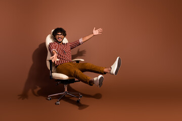 Full body portrait of nice young man sit chair empty space wear striped shirt isolated on brown...