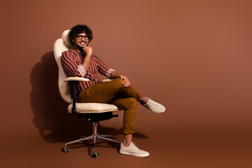 Full body portrait of nice young man sit chair think empty space wear striped shirt isolated on...