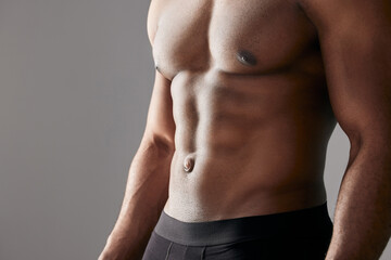 Fototapeta premium Abdomen, muscle and man in studio for fitness, exercise and body health closeup isolated on white background. Abs, shirtless and strong bodybuilder workout for energy, sport or power for wellness