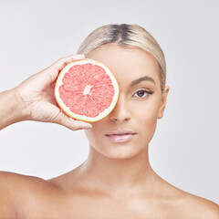 Woman, portrait and skincare with grapefruit for natural beauty on a gray studio background. Face...