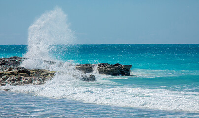 Waves crash along the rocks in the turquoise waters of the Caribbean Sea in the Bimini Islands, Bahamas.