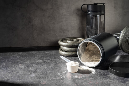 Amino acid food supplement, creatine powder in a measuring scoop and plastic jar, copy space