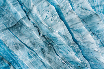 Aerial view of a glacier, capturing the intricate patterns and textures formed by the ice. Highlight the natural lines and subtle color variations to create a minimalist, abstract composition.