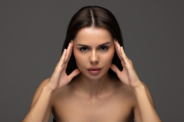 Fototapeta premium Portrait of woman with natural nude make up with bare shoulders on gray background.