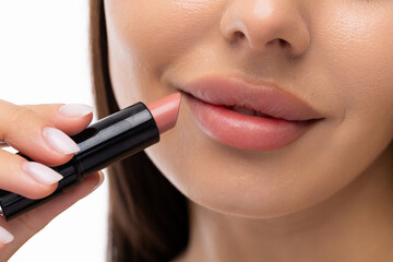 Young woman apply a lip gloss on her lips on white background