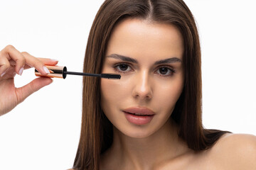 Young woman putting eye liner on eyelid on white background