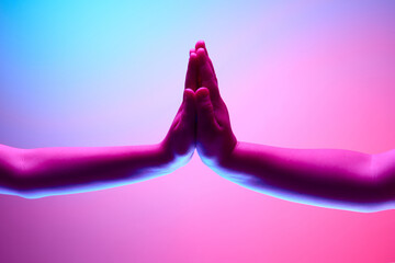 Two kids hands giving high five against multicolored background in neon light. Success, positivity,...
