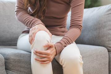 Young Asian woman touching her knee feel pain when move.