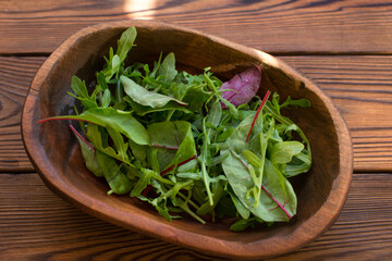 salad of arugula leaves and beetroot leaves in a wooden plate. Healthy eating
