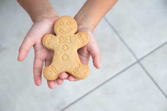 Manos de niño sostienen una galleta de jengibre - Powered by Adobe