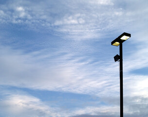 silhouette of two square light boxes street lamp on post against cloudy sky