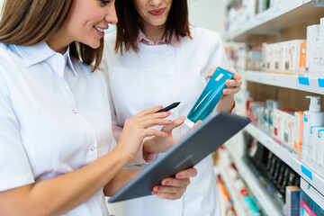 Two beautiful pharmacists working together in a drug store and doing a stock take. Portrait of a...