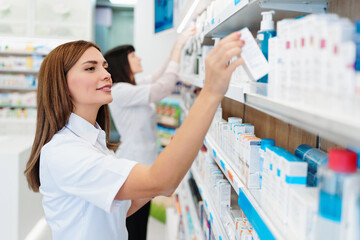 Two beautiful pharmacists working together in a drug store and doing a stock take. Portrait of a...