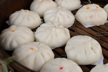 Bamboo basket of hot steamed barbecue pork bun, minced pork bun and sweet cream bun, Chinese dim sum traditional food style.