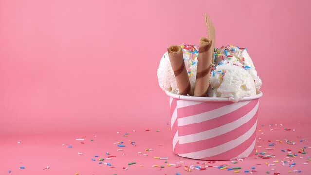 scoops of ice cream in bowl with strewed sprinkles and cookies on pink background, summer creative concept, copy space