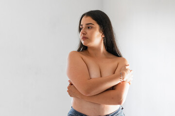 latina woman covering her breasts with her hands while looking to the side, on a white background