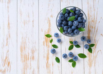 Fresh organic blueberry in a bowl on a wooden table. Concept of healthy eating. Top view, copy space.