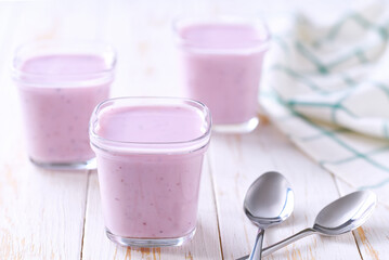 Three portions of homemade fruit yogurt in a jars on a white table, selective focus.