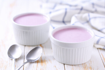 fruit yogurt in a ceramic bowl with spoon on a light background, selective focus.