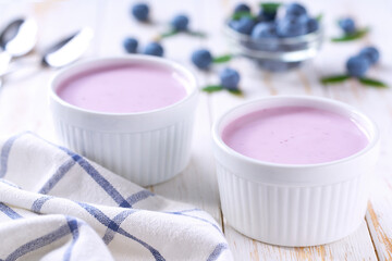 fruit yogurt in a ceramic bowl with fresh blueberries on a light background, selective focus.