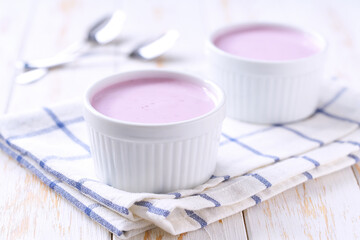 blueberry homemade smoothie in a ceramic bowl with spoon on a white table, selective focus.