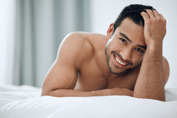 Portrait, morning and Asian man lying in bed with smile for relax, wellness and wakeup in bedroom....