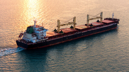 A bulk carrier freight ship at traveling on full motion over blue sea . Aerial view drone photo