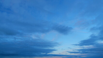 Different shades sky with gray clouds. Twilight time. Widescreen panorama of sunset sky. Timelapse.