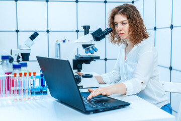 young female laboratory assistant working with computers and microscope