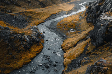 Aerial view of a narrow mountain stream winding through a rocky landscape. Focus on the simplicity of the clear water cutting through the rugged terrain.