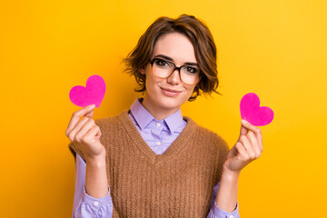 Portrait of lovely adorable woman wear knit waistcoat in glasses hands hold two pink heart...