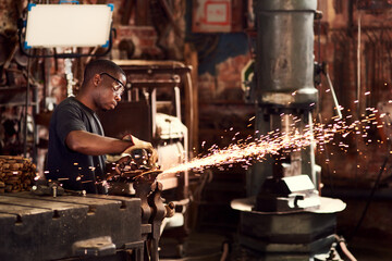 Blacksmith, factory or black man in workshop and sparks, manual labor for safety on hot steel with...