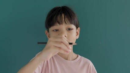 Portrait of a Thai Asian kid girl, aged 8 to 10 years, with a cute and bright face. imagining By using pencils to write books and draw pictures in the air. It is a happy learning experience.