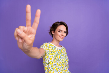 Portrait of pretty young woman demonstrate v-sign wear t-shirt isolated on purple color background