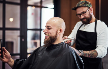 Beard, client and man in barbershop with smile, cut and tools for trendy facial hair care at small business. Style, barber and customer in chair for grooming service, haircut skills and clean trim