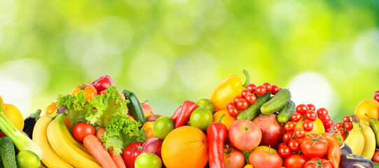Panorama multicolored fresh fruits and vegetables on green background.