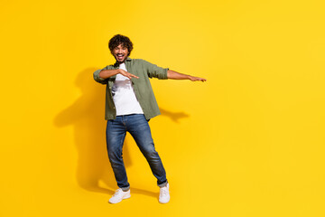 Portrait photo of young funny indian carefree guy in khaki shirt dancing summer music vibes isolated on yellow color background