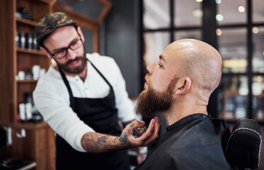 Beard, client and man in barbershop with hair care, cut and tools for trendy facial shave at small business. Style, barber and customer in chair for grooming service, haircut skills and clean trim