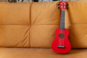 A red ukulele placed on top of a couch
