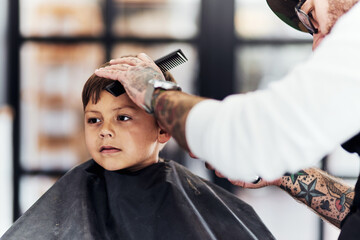 Barbershop, man and child with scissor, comb and hairdresser treatment at salon with barber. Kid,...