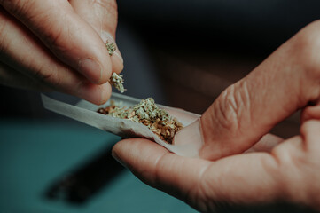 man putting some cannabis on a rolling paper