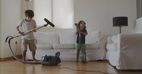 Three kids are joyfully cleaning a living room with a vacuum, appearing to dance and enjoy their housework.