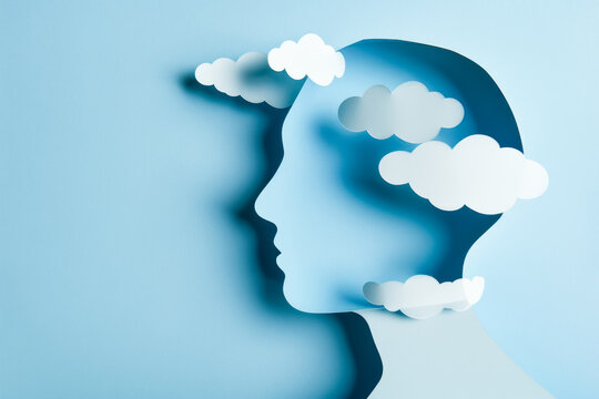 Human head with white clouds around it. Layers of paper cut out in blue and white. Concept of mental health and psychology. With copy space.