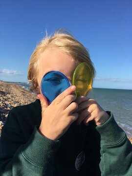 Child Playing With Colorful Lenses on a Sunny Beach