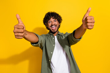 Portrait photo of young funny mexican overjoyed party guy in khaki shirt showing likes to you...