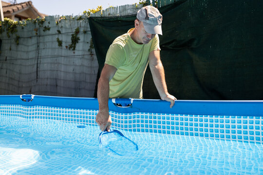 Man cleaning swimming pool in the garden.