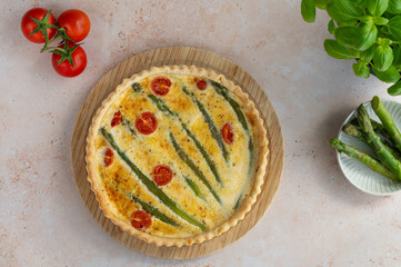 Homemade tart with green asparagus and cherry tomatoes on a stone background. Food photography. Quiche with green asparagus, eggs and parmesan cheese.