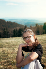 Girl with glasses outdoors in the mountains in summer. Nature and children. Children and glasses