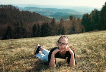 Girl with glasses outdoors in the mountains in summer. Nature and children. Children and glasses